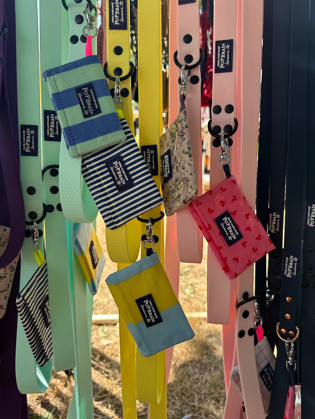 Popbrain waterproof PVC dog waste bag holders in various colors and patterns hanging from matching leashes