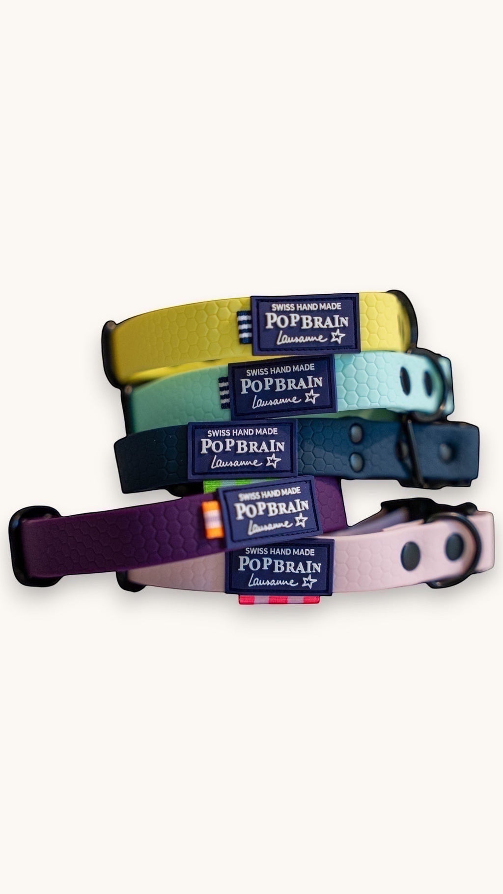 Stack of Popbrain waterproof PVC dog collars in yellow, mint, navy, purple, and pink with matte black hardware